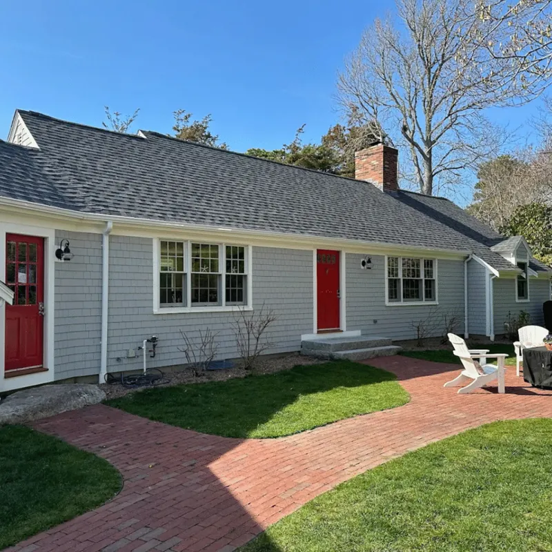 Gray cape with red doors and a brick walk
